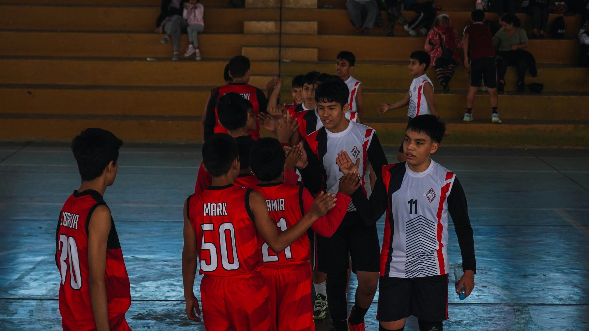 A group of young men standing next to each other on a basketball court