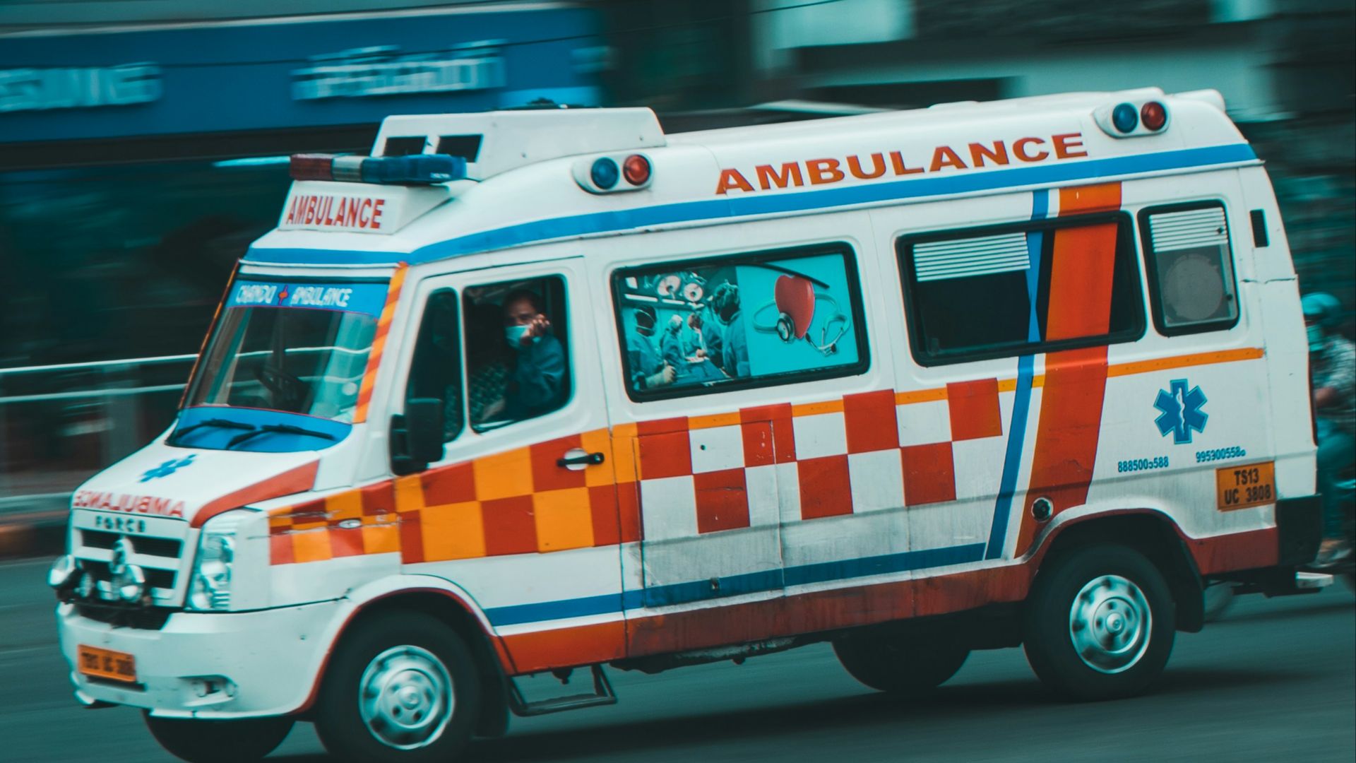 an ambulance driving down a street next to tall buildings