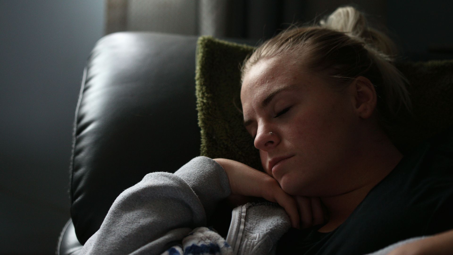 boy in gray hoodie lying on black leather couch
