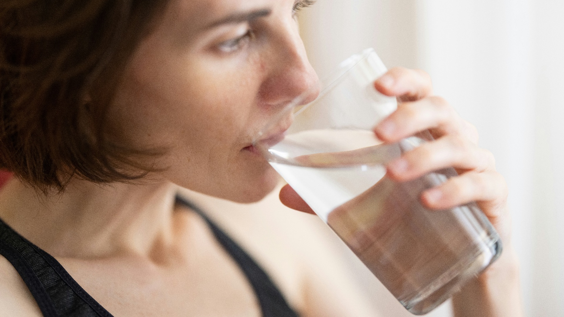 woman in black tank top drinking water
