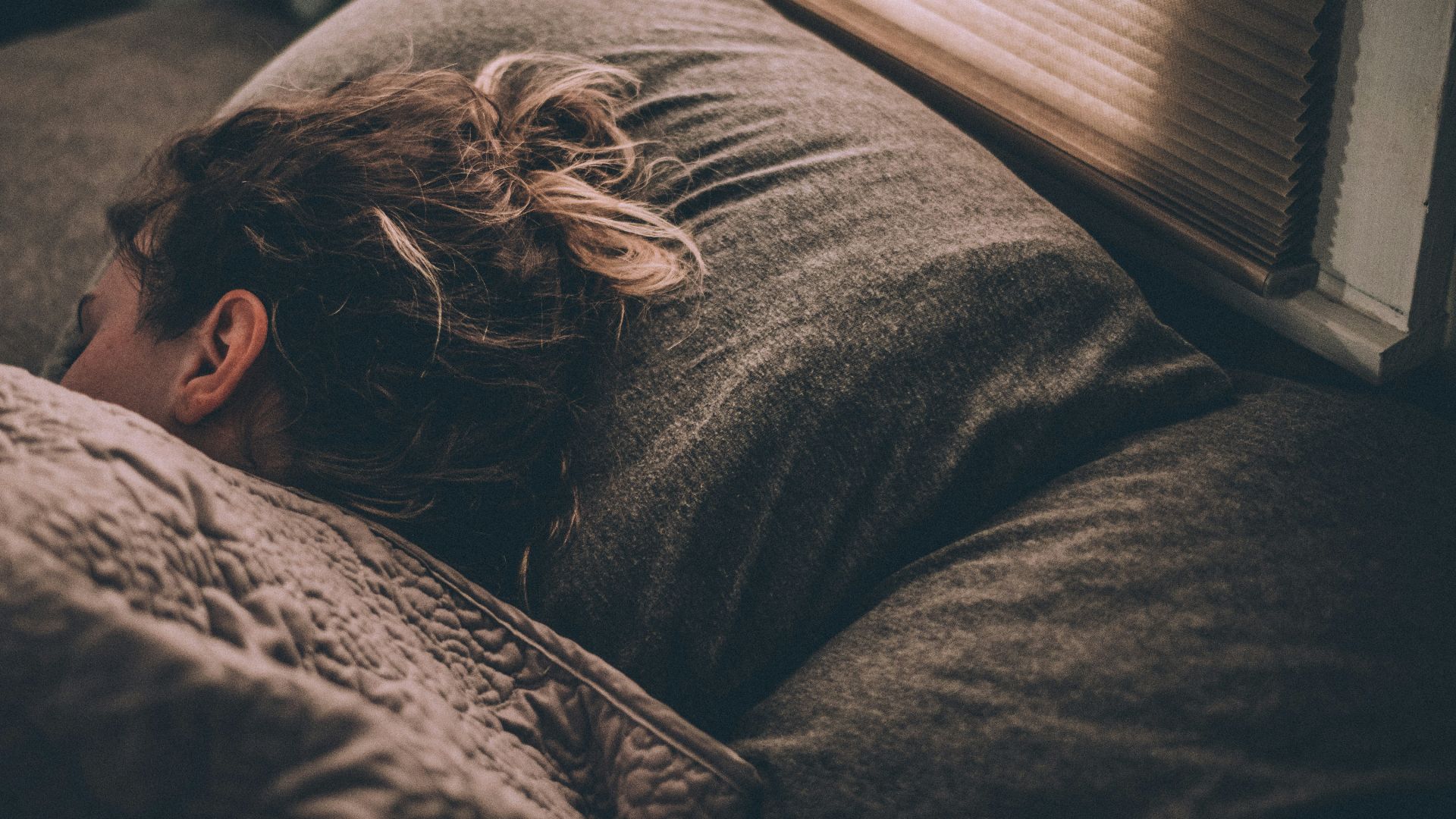 woman sleeping on bed under blankets