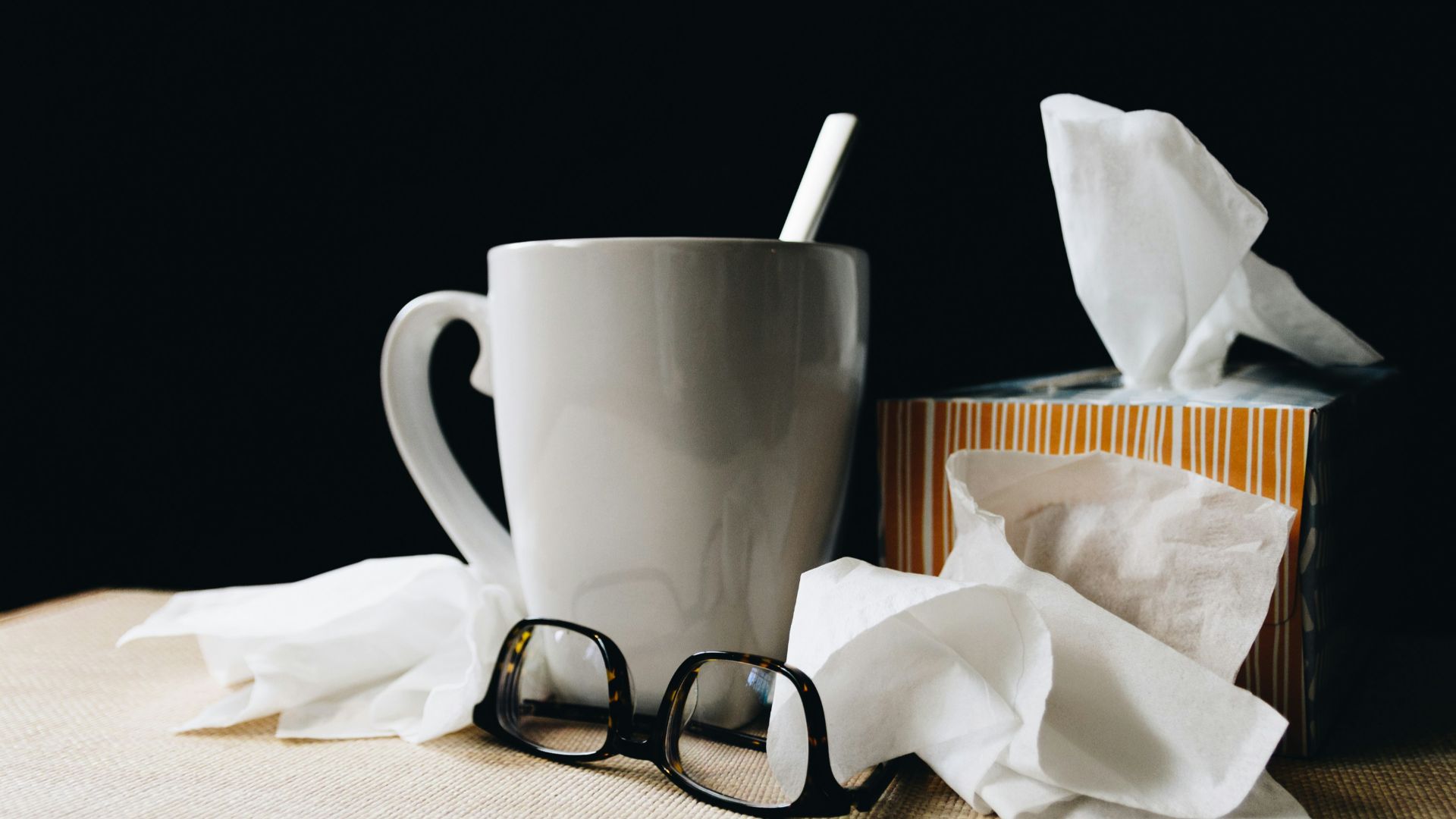 white ceramic mug on white table beside black eyeglasses