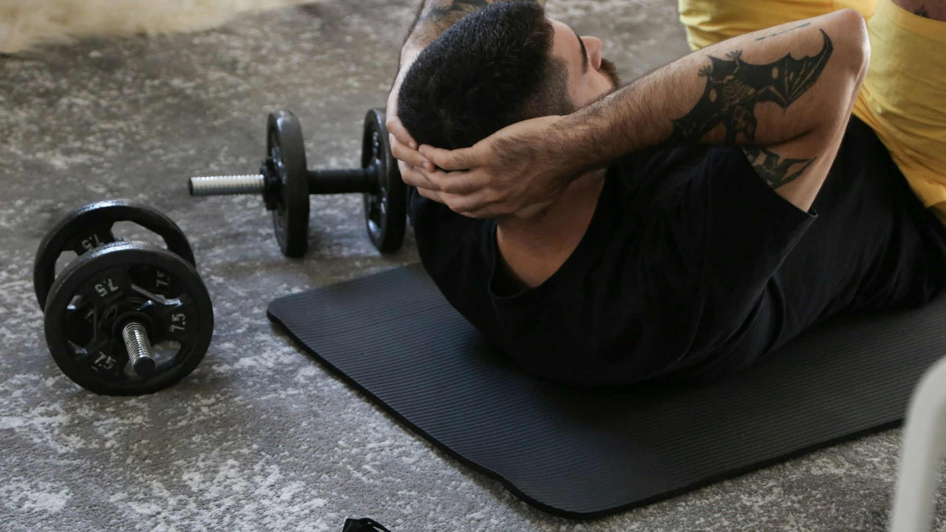 a man is doing exercises on a mat with a barbell