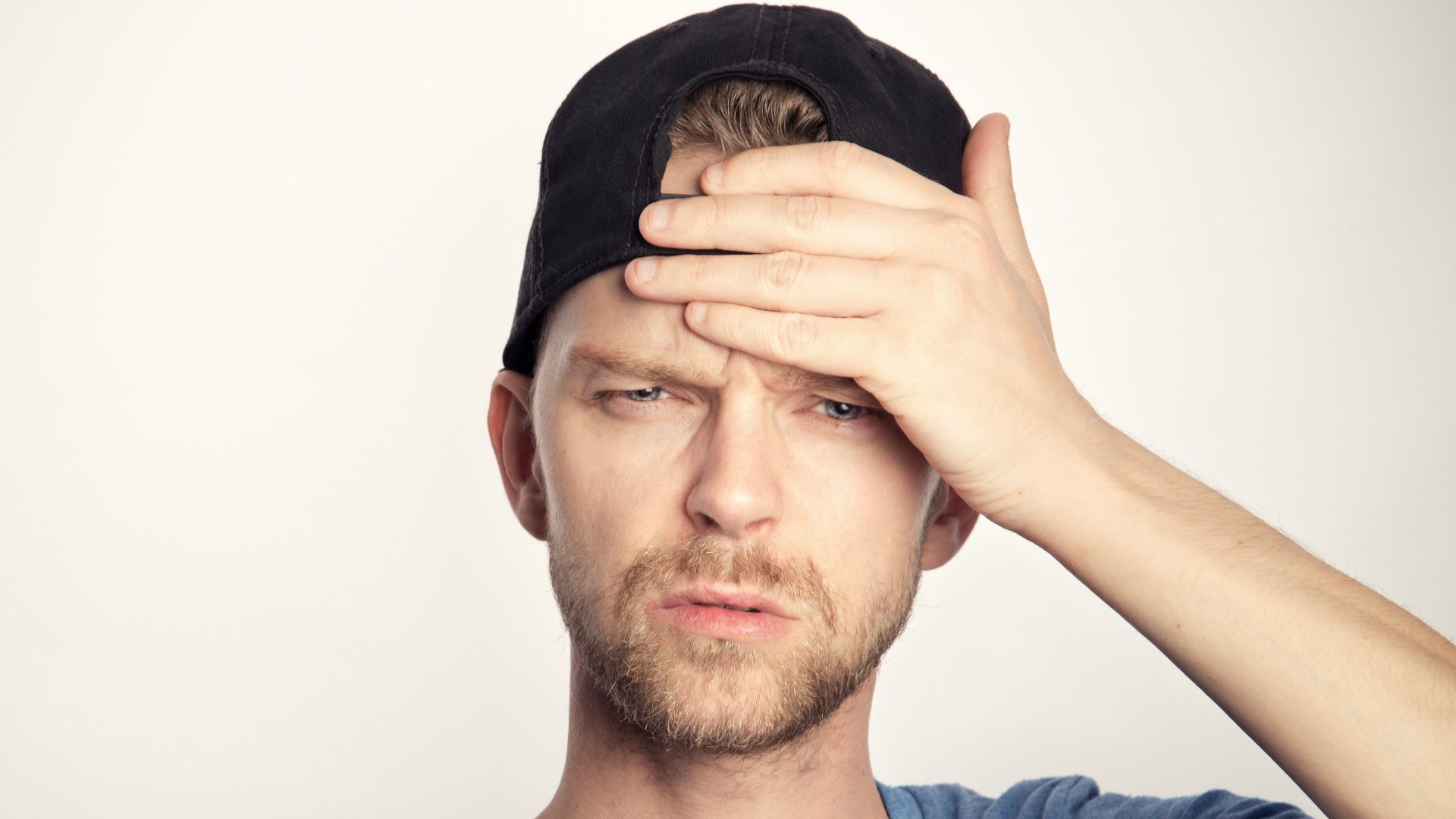 man in blue crew neck shirt covering his face
