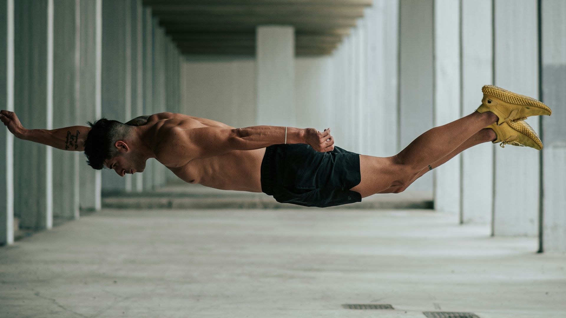 a shirtless man is diving in a parking garage
