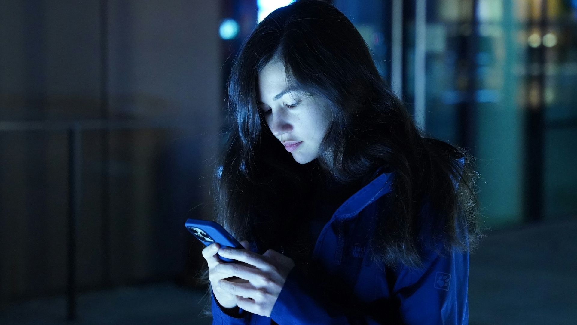 a woman in a blue jacket looking at her cell phone