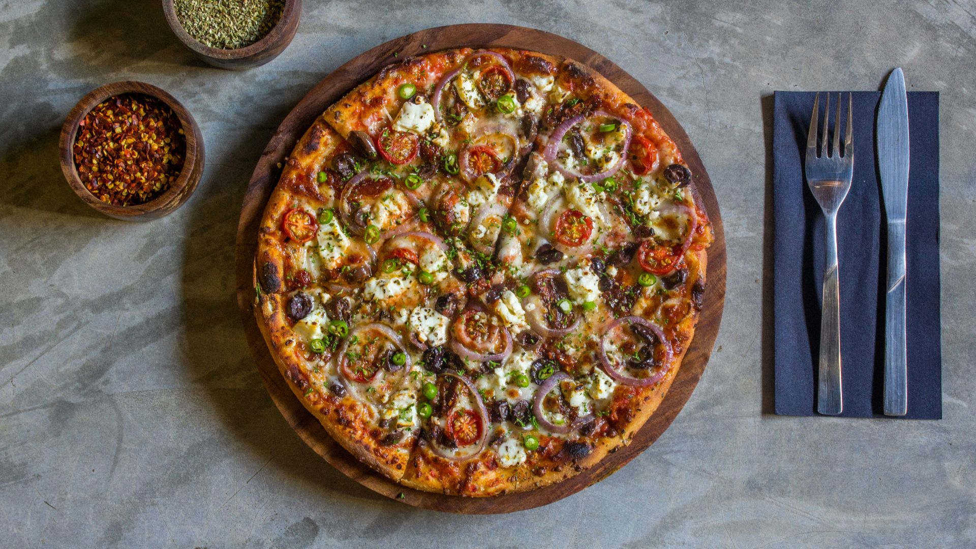 A pizza sitting on top of a table next to a fork and knife