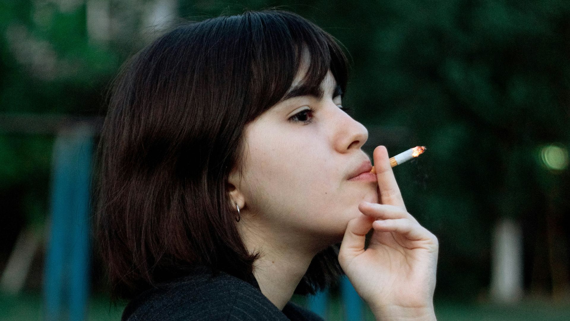woman in black long sleeve shirt smoking cigarette