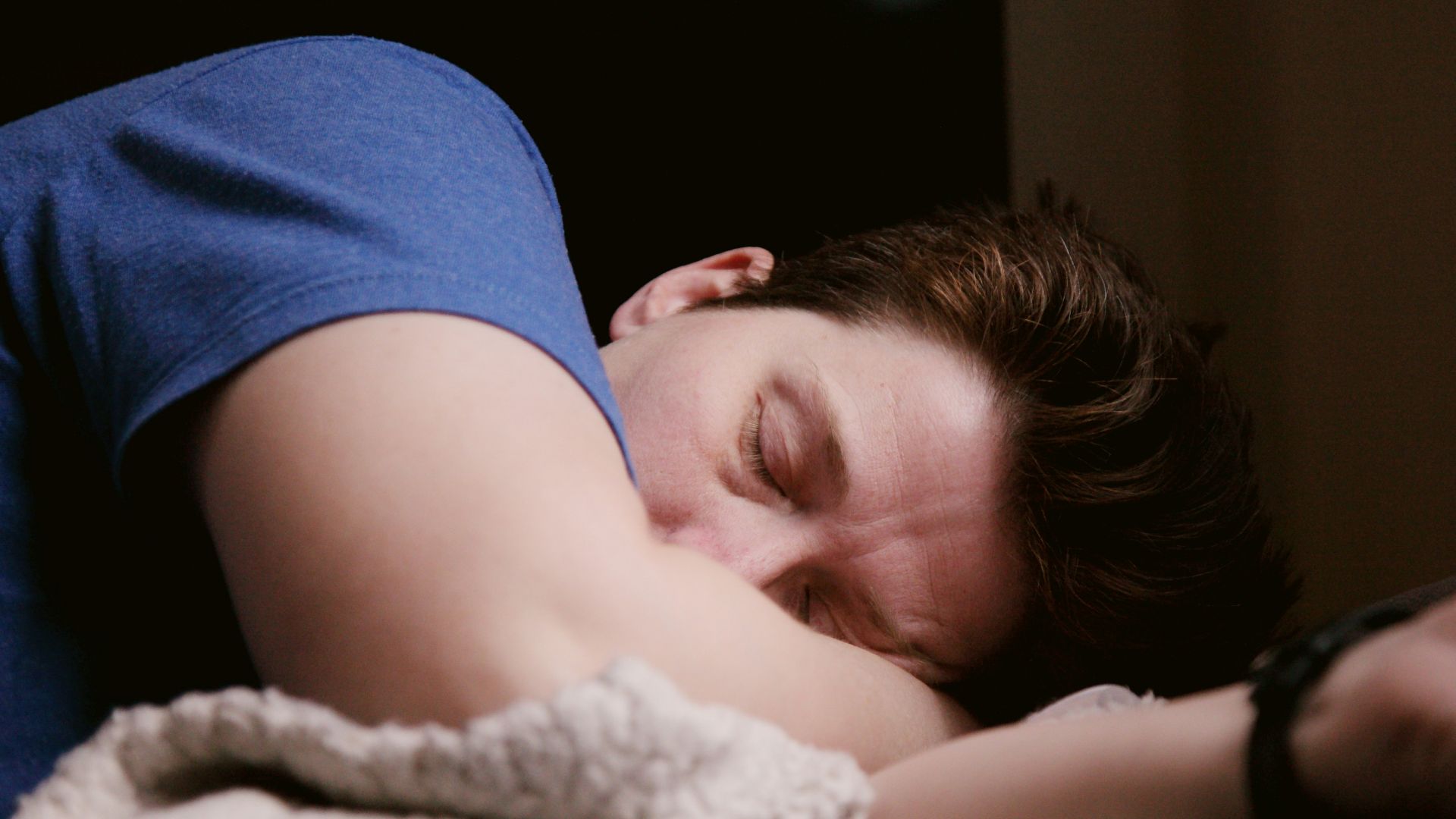 woman in blue shirt lying on bed
