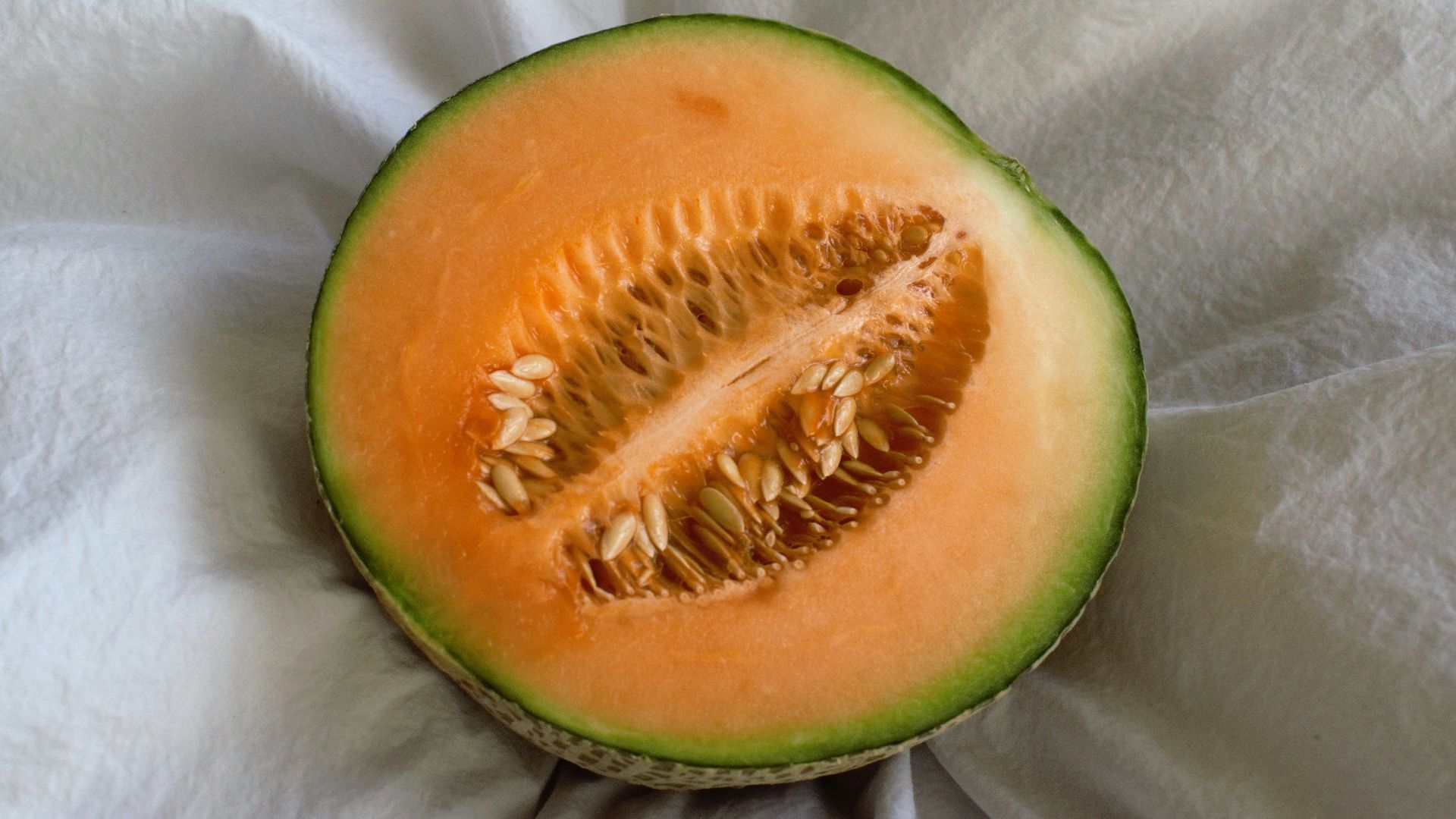 a cut in half melon sitting on top of a white cloth