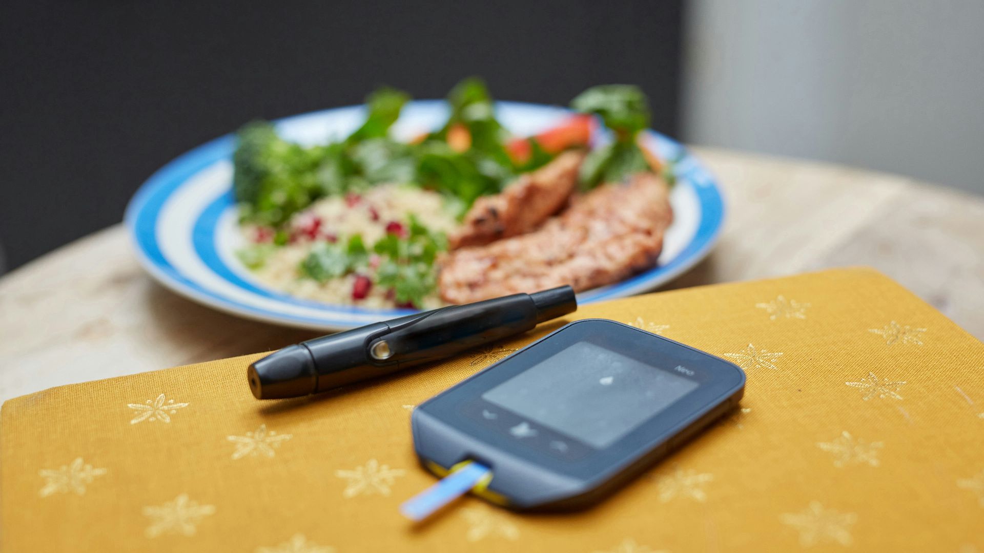 a plate of food and a Glucometer on a table