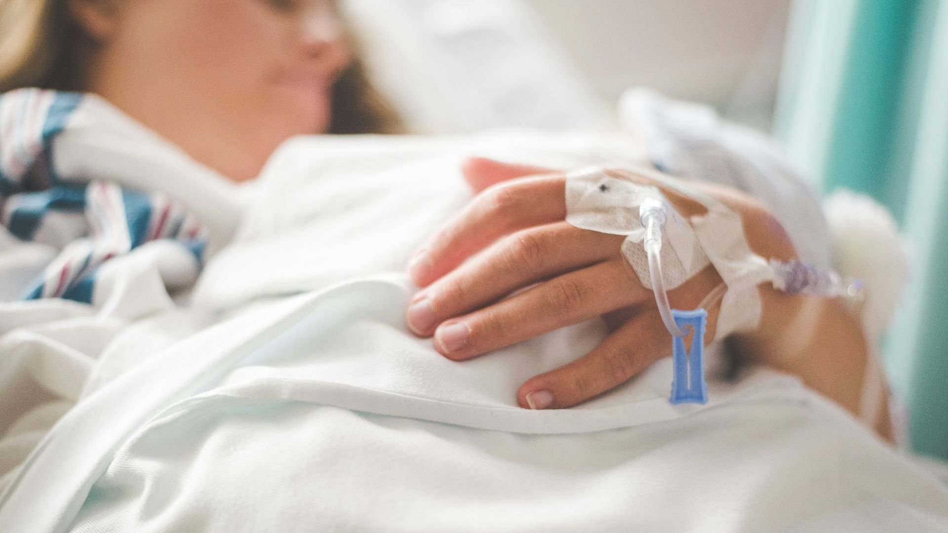 a woman laying in a hospital bed with an iv in her hand