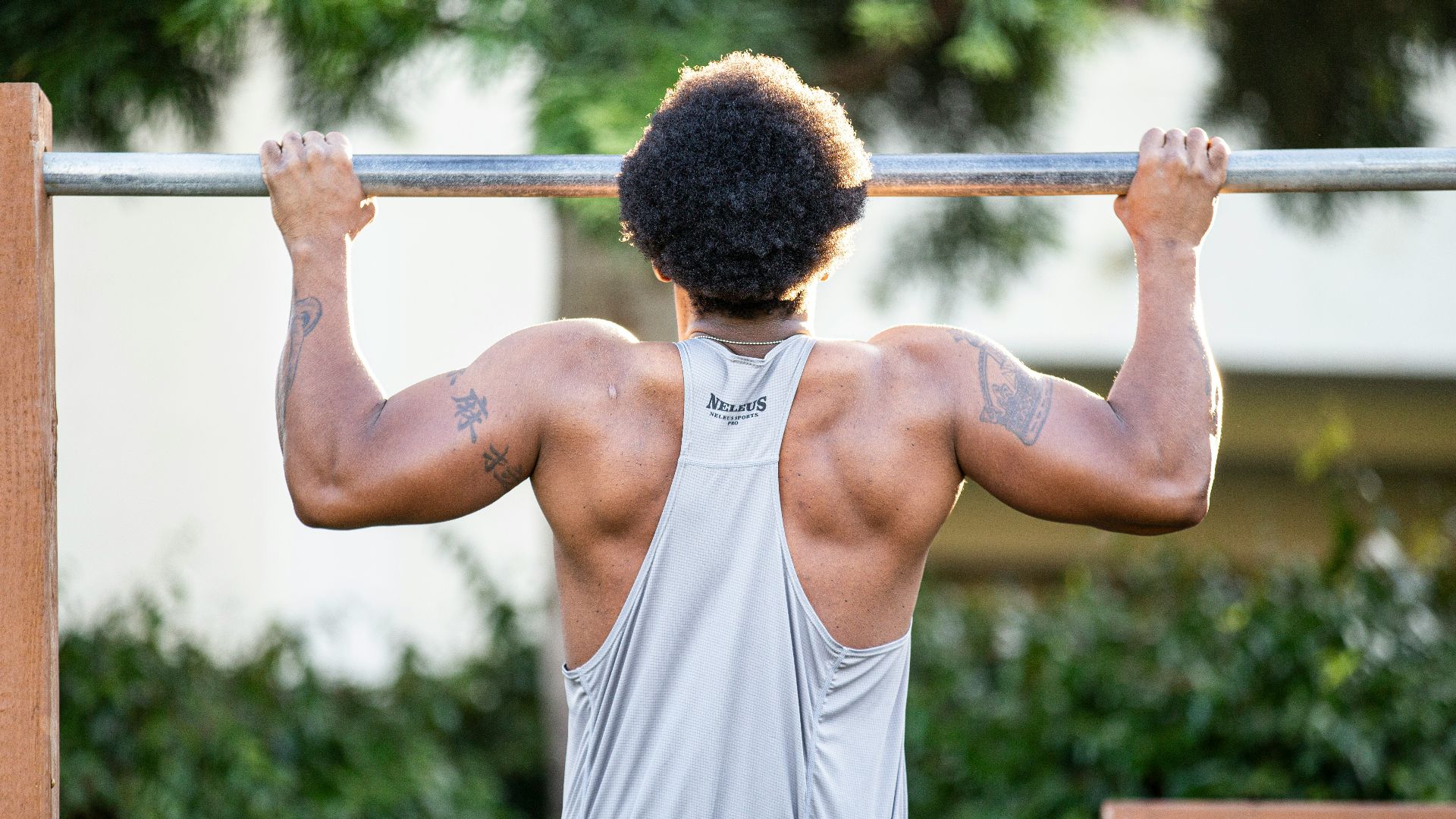 man in gray tank top holding gray metal bar