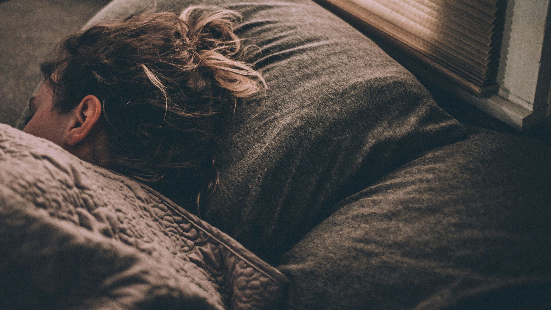 woman sleeping on bed under blankets