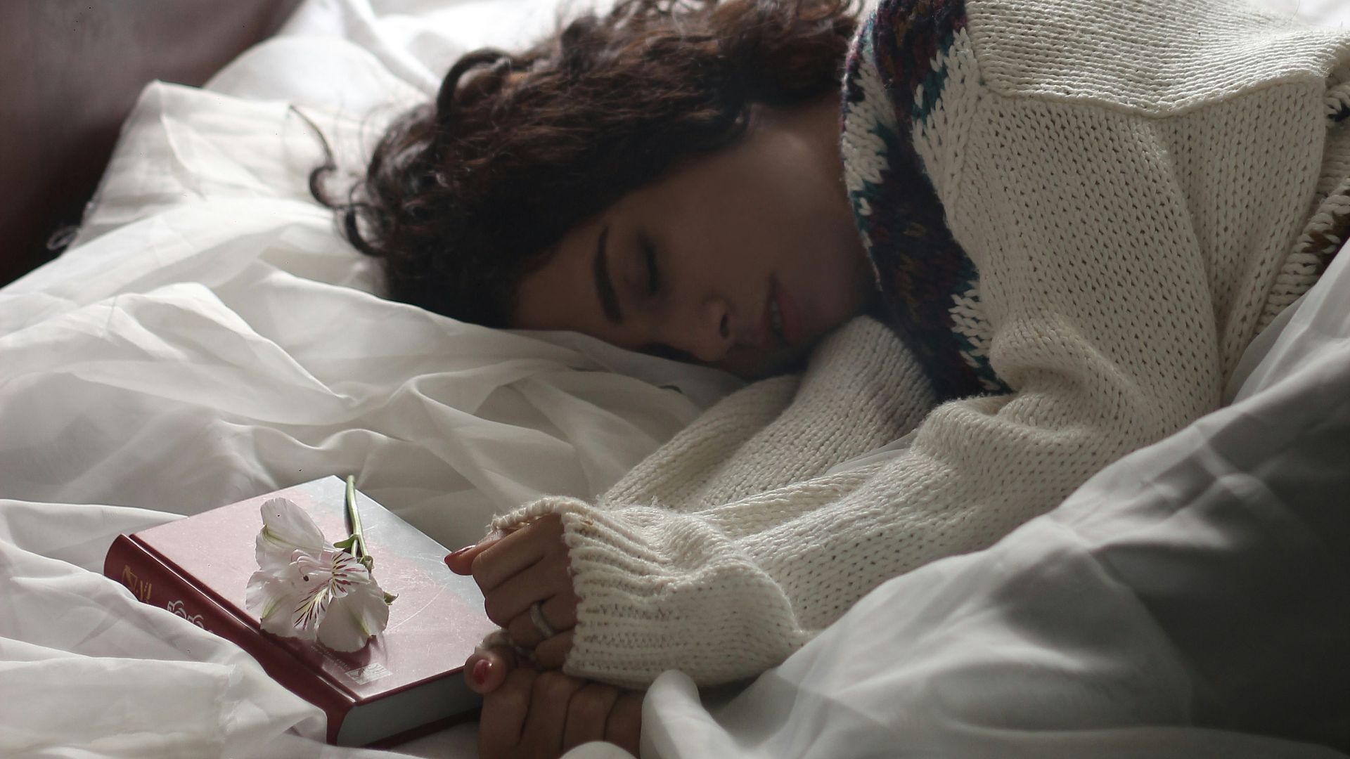 woman sleeping on bed beside book