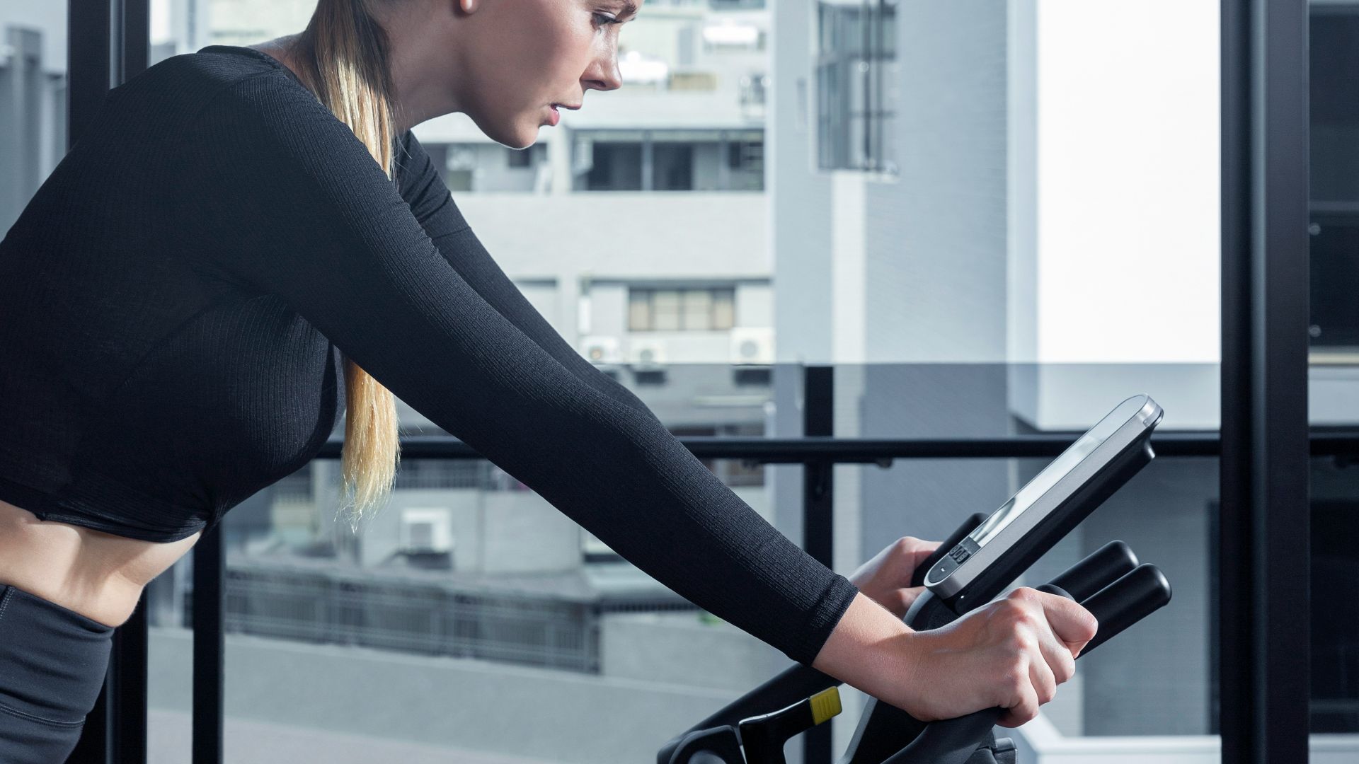 a woman on a stationary bike using a tablet