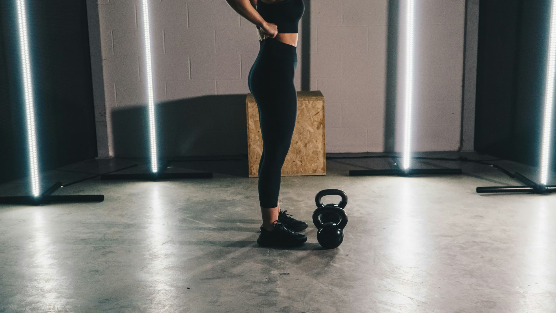 woman in black tank top and black leggings standing on white floor