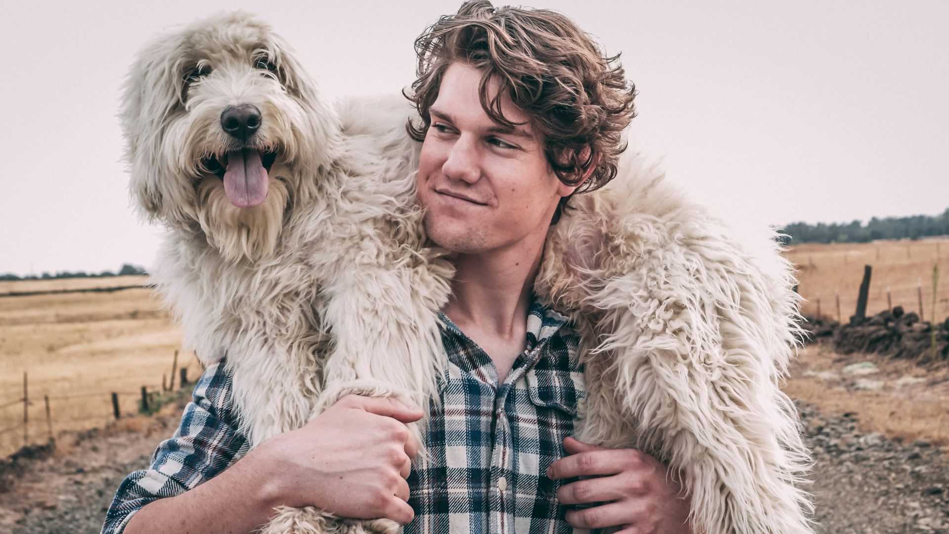 man carrying long-coated white dog