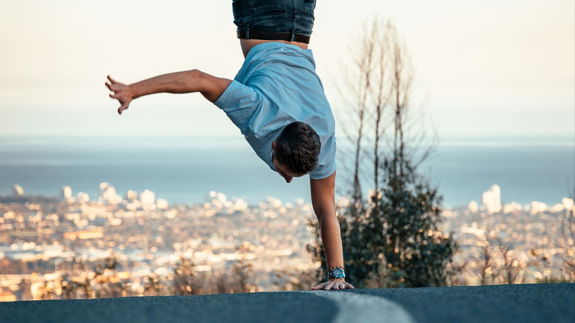 woman in blue denim jeans and white shirt standing on gray concrete wall during daytime