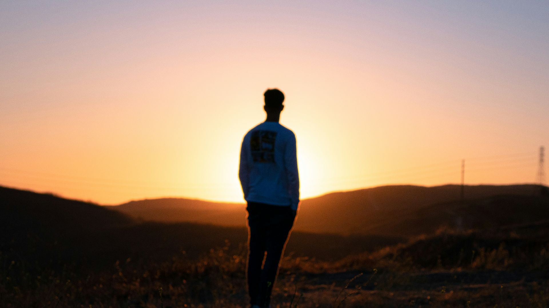 man in blue shirt standing on brown field during sunset