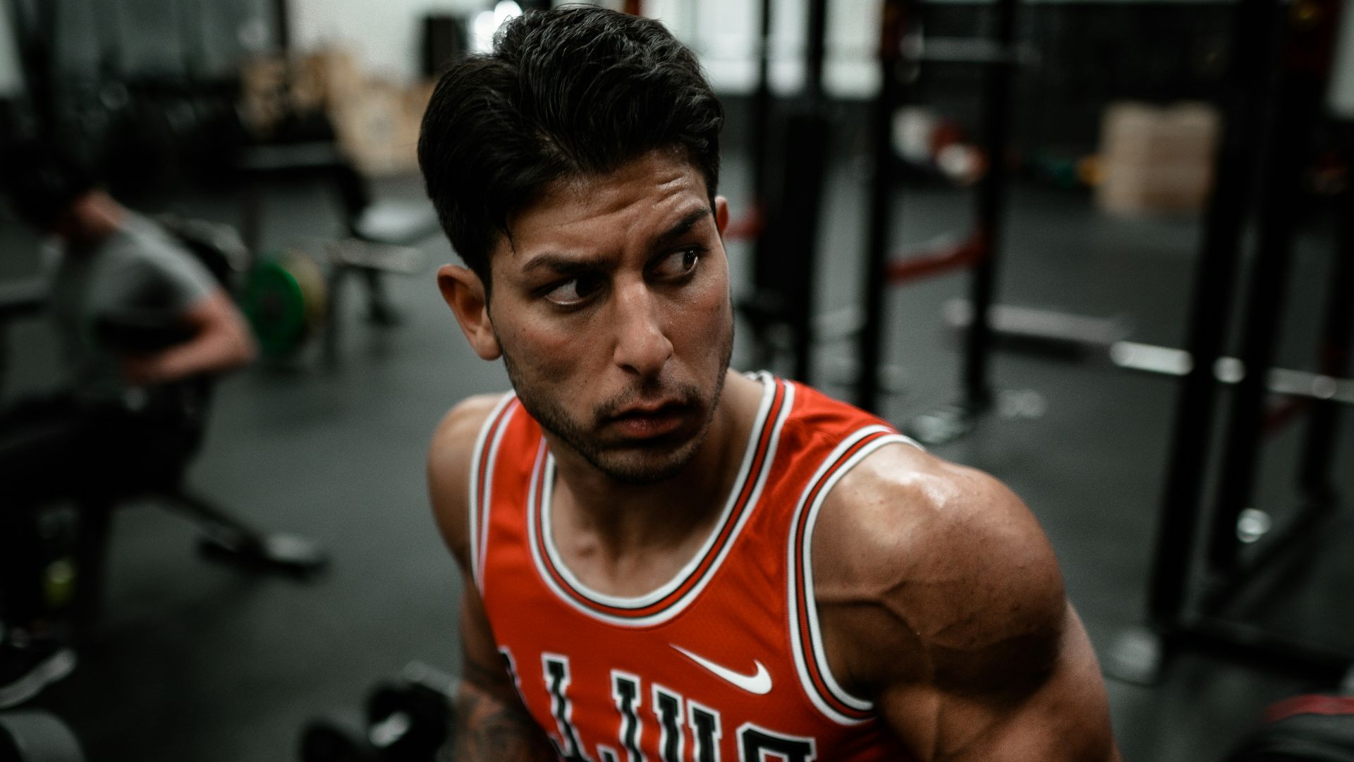 man in red Chicago Bulls jersey doing push-up exercise on dumbbells