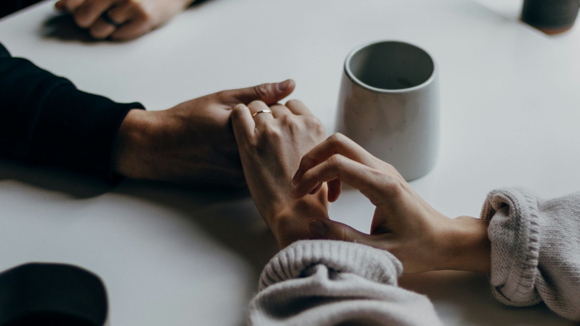 person in black long sleeve shirt holding white ceramic mug