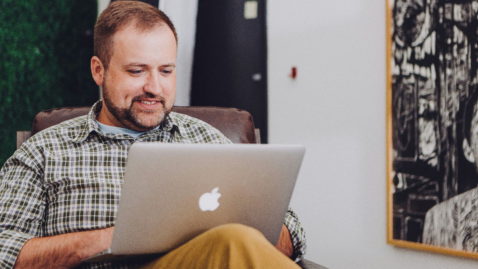 man smiling and using MacBook