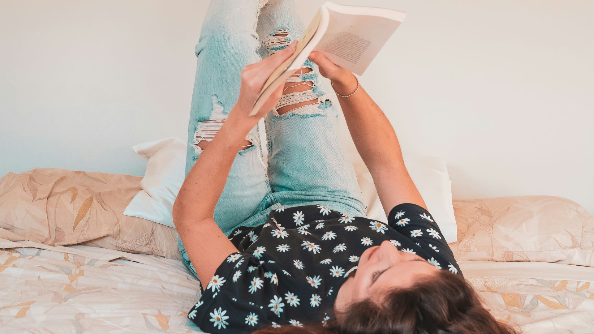 a woman lying on a bed reading a book