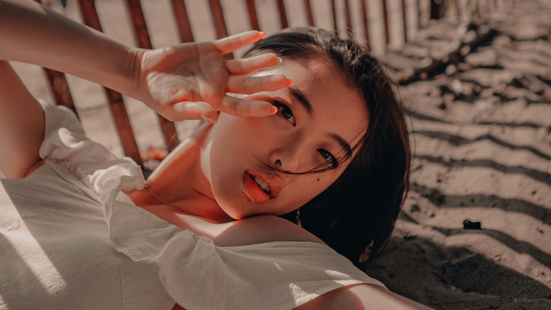 woman in white dress lying on sand during daytime