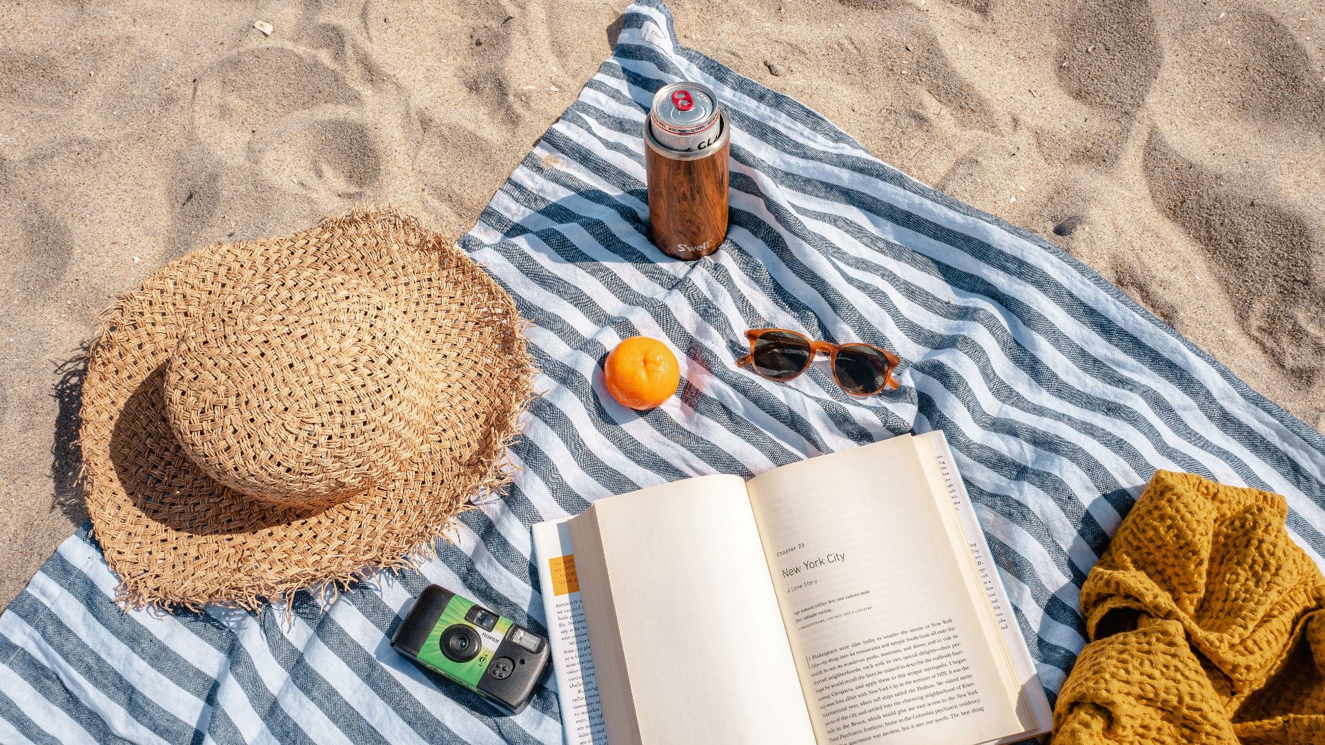 brown glass bottle beside white book on blue and white textile