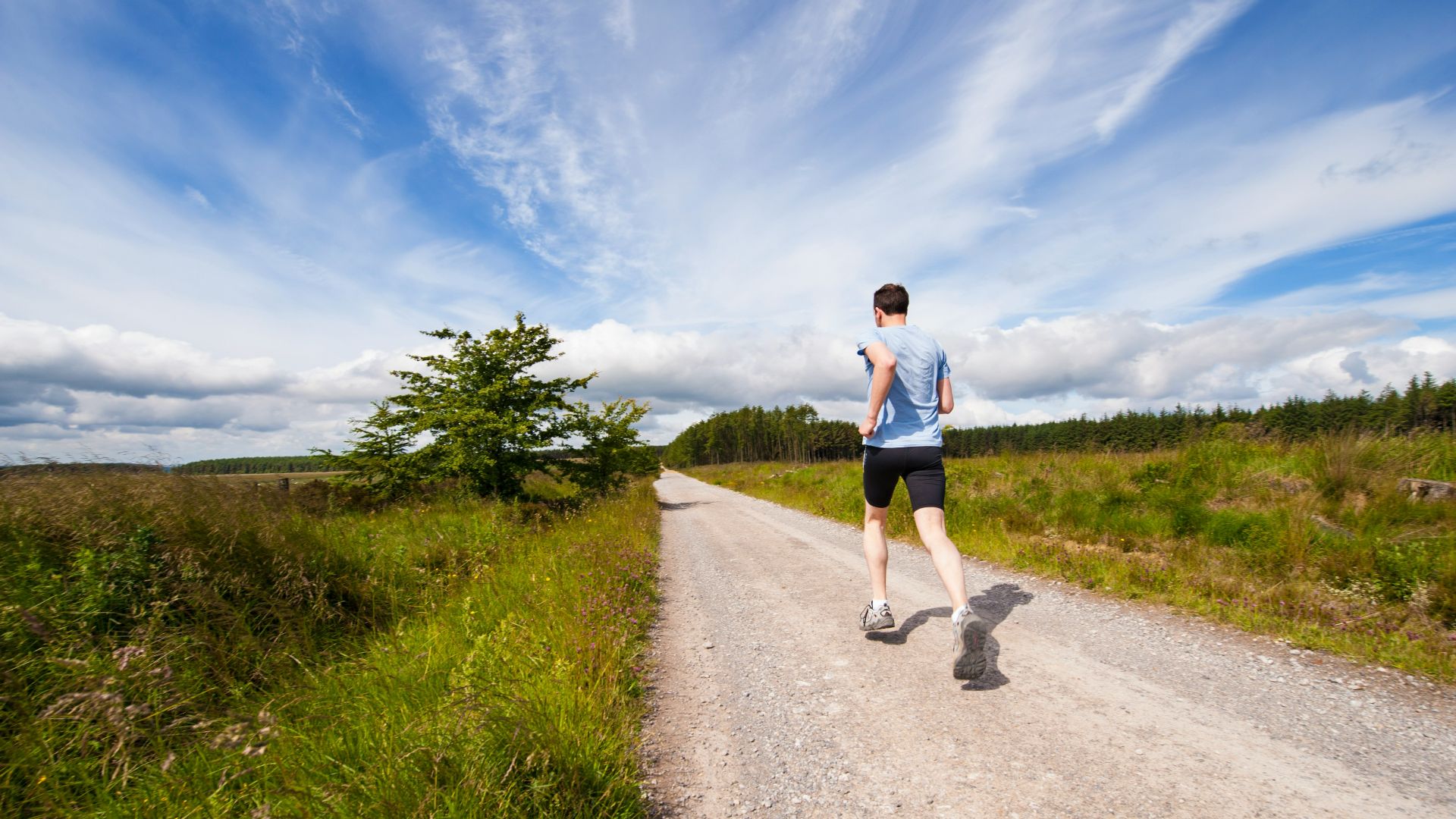man running on road near grass field