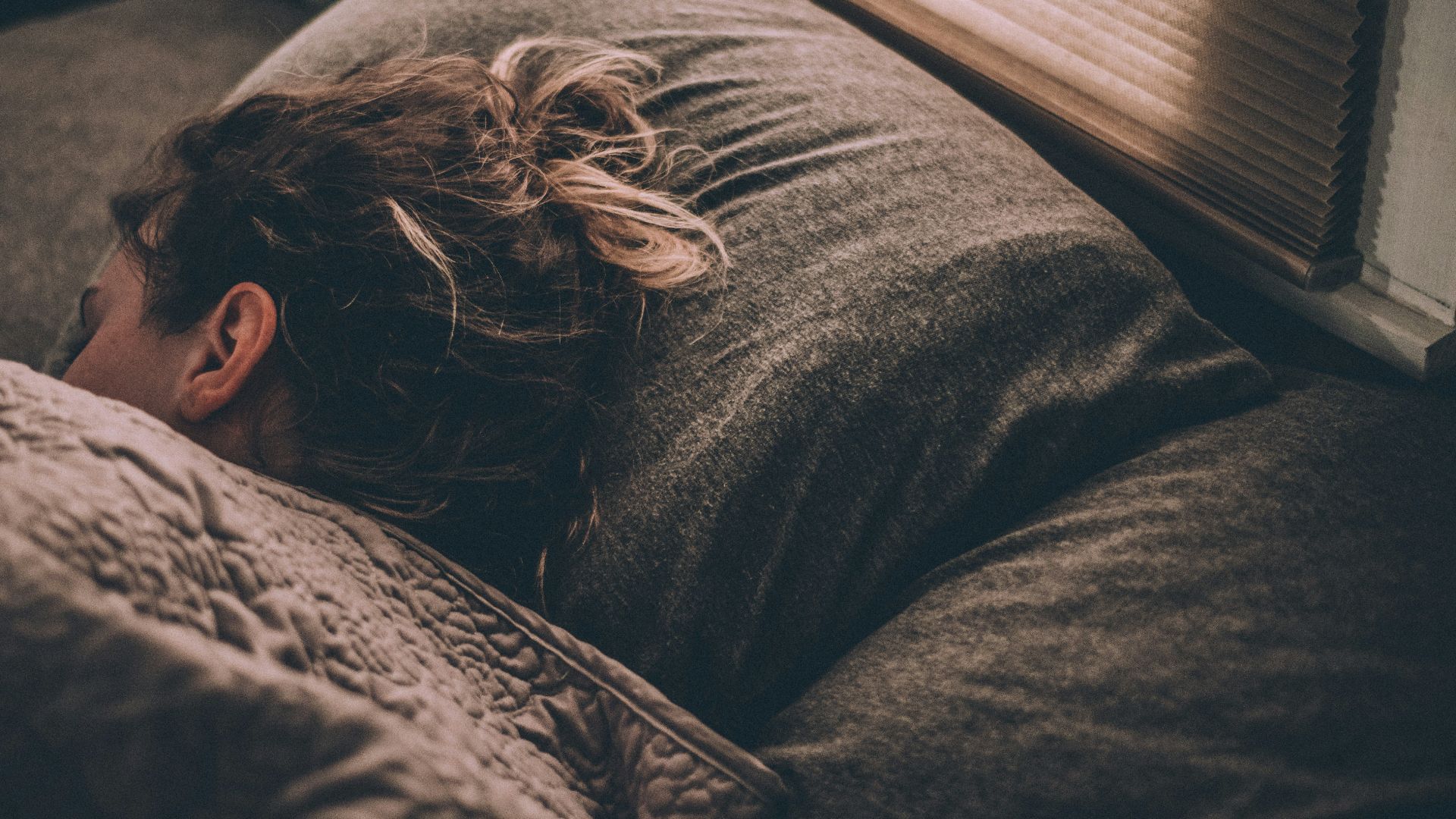 woman sleeping on bed under blankets