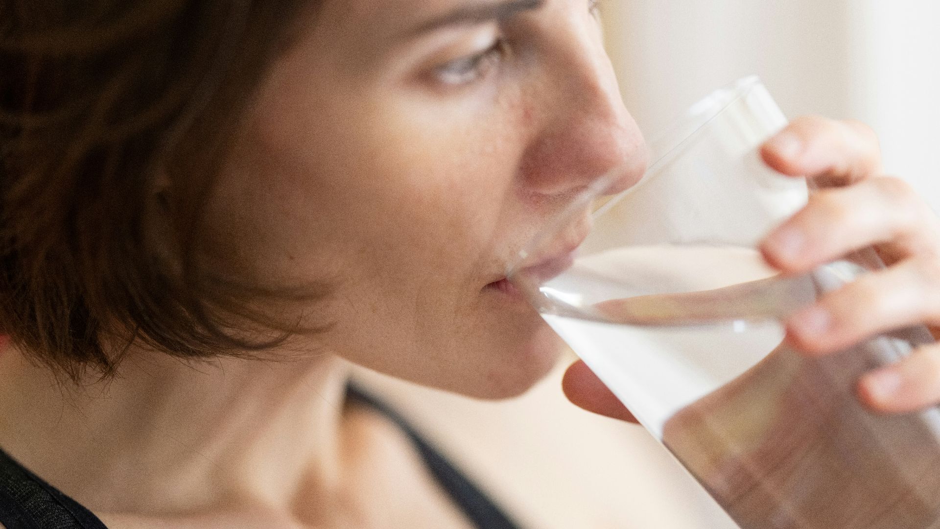 woman in black tank top drinking water