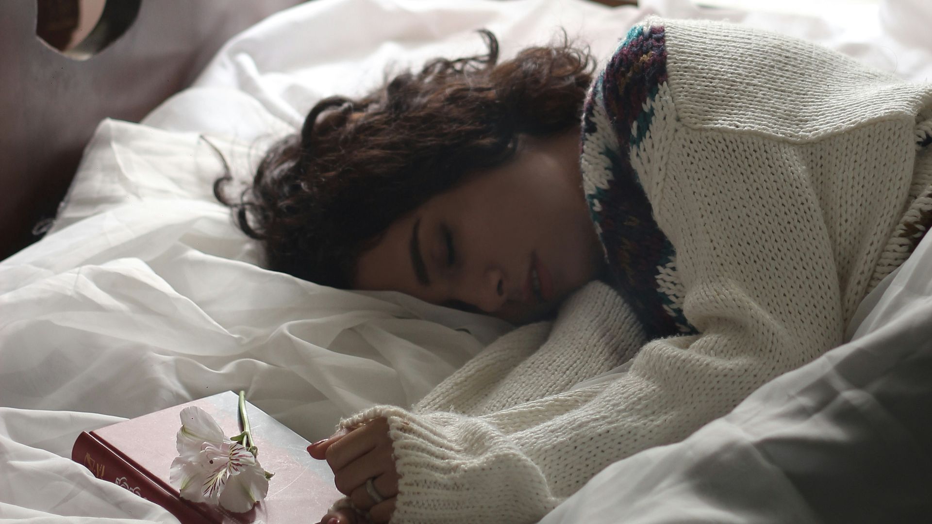 woman sleeping on bed beside book