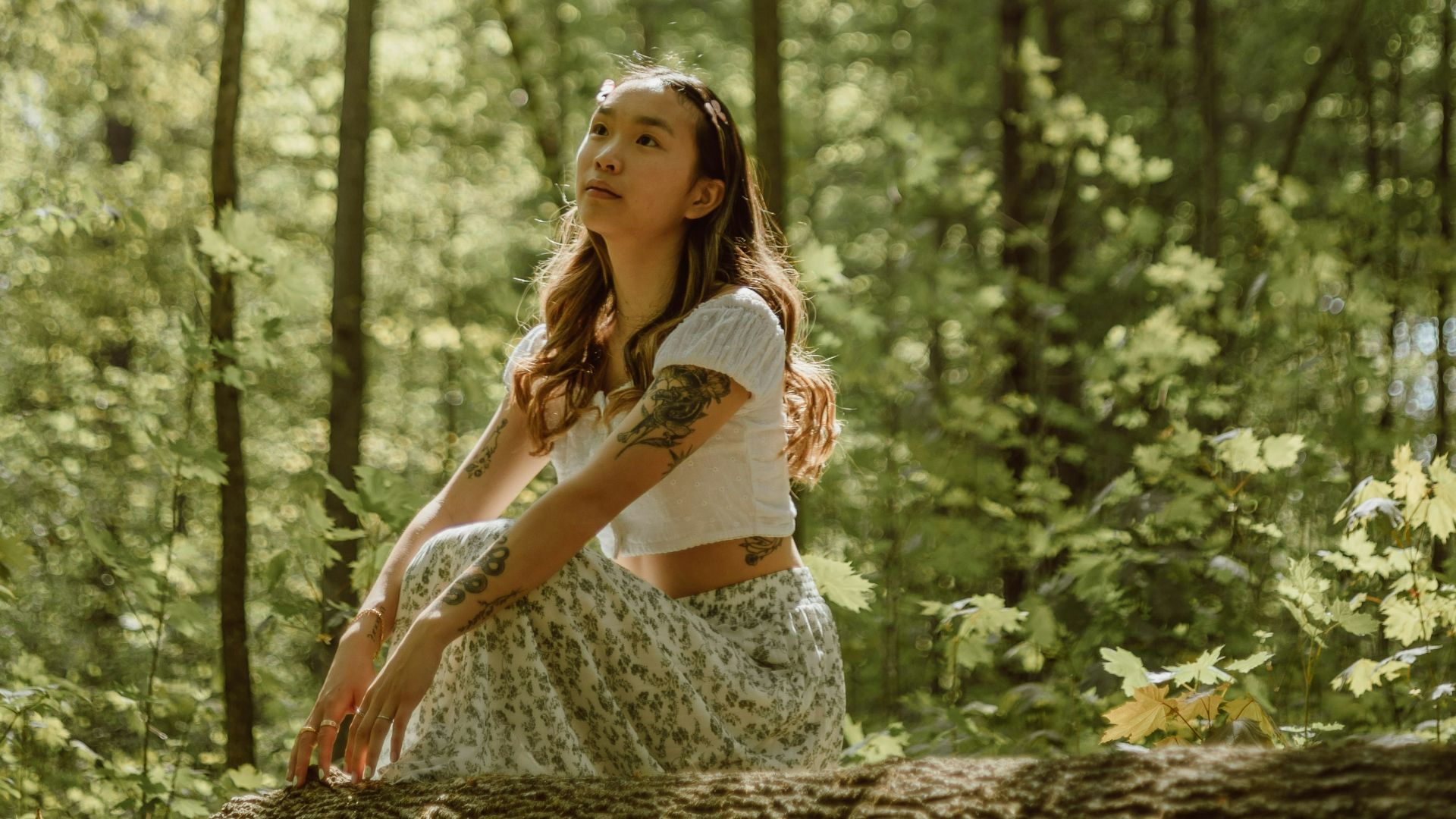 woman in white tank top and white floral skirt standing on forest during daytime