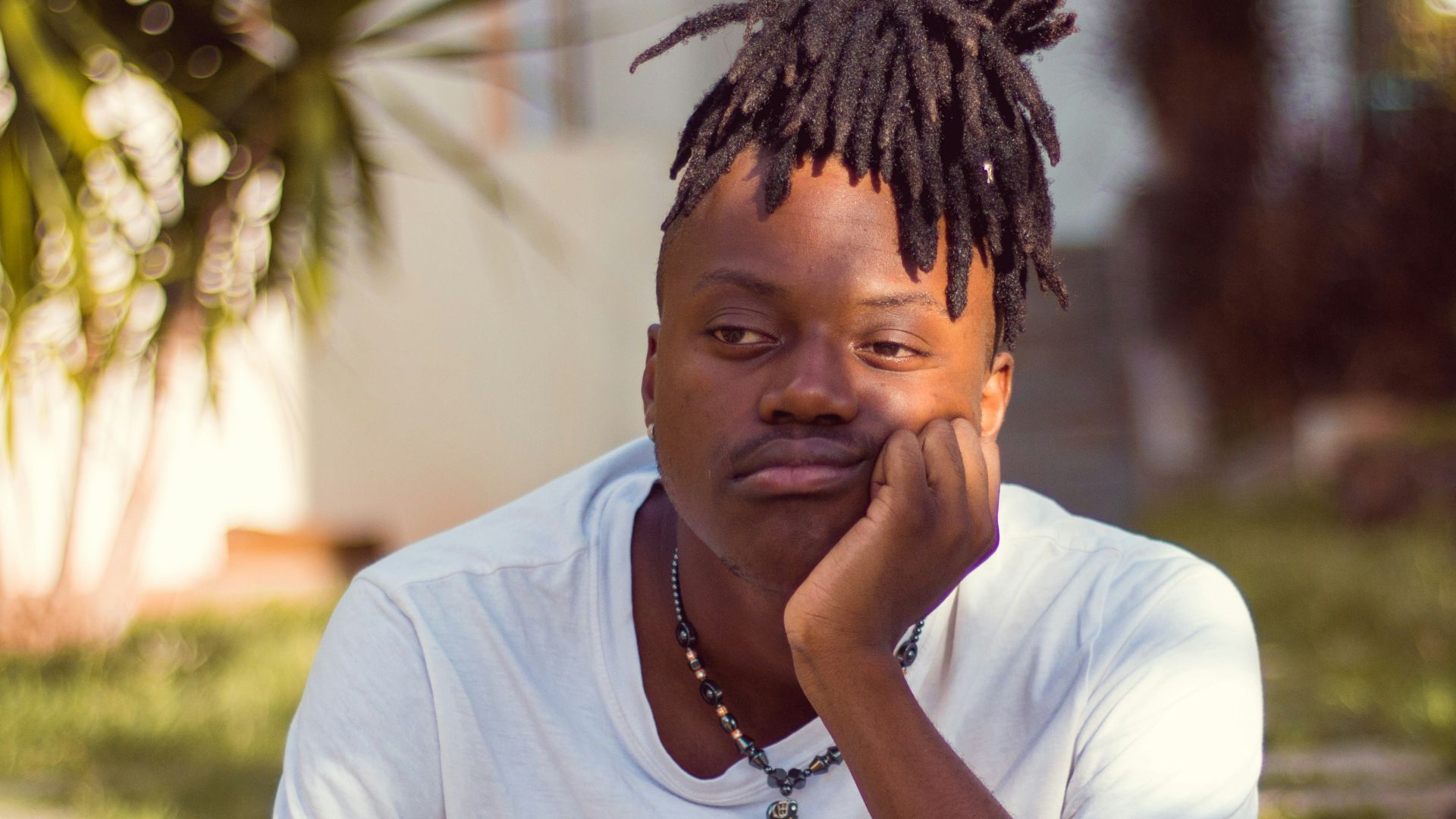 man in white crew neck t-shirt sitting on brown wooden chair