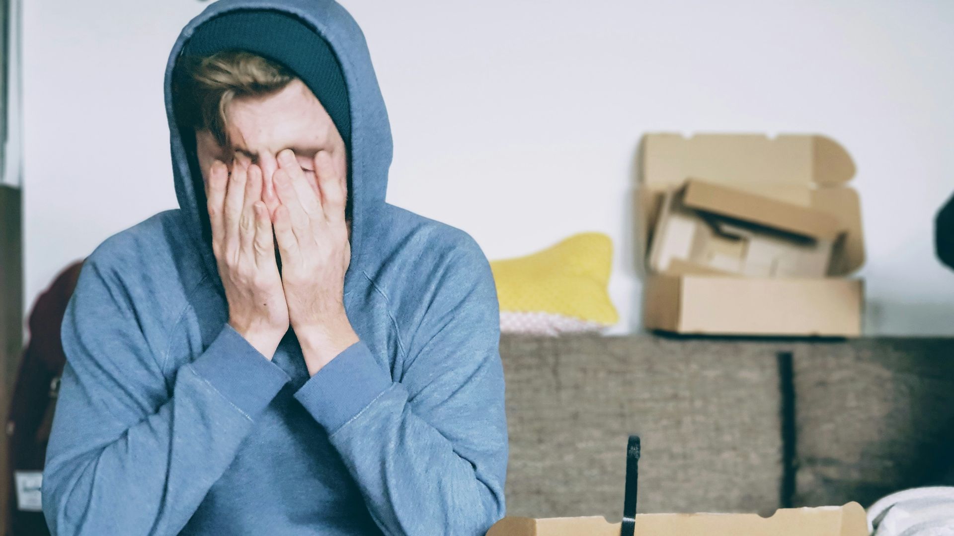 man covering face with both hands while sitting on bench