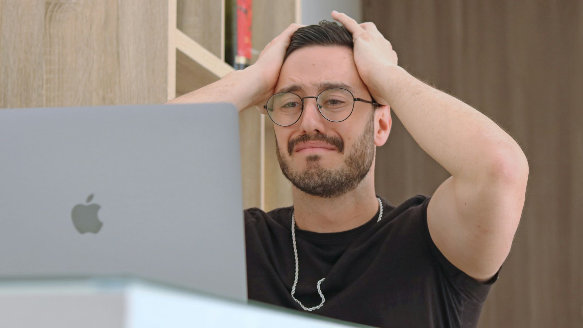 a man with glasses is looking at a laptop