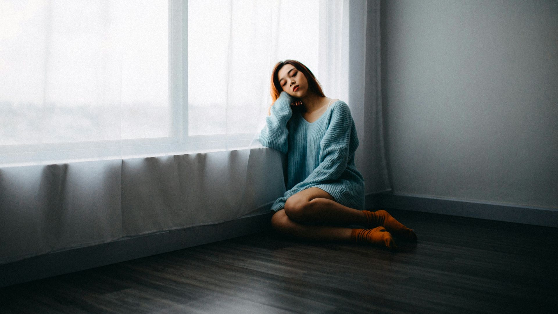 woman sitting on floor near window