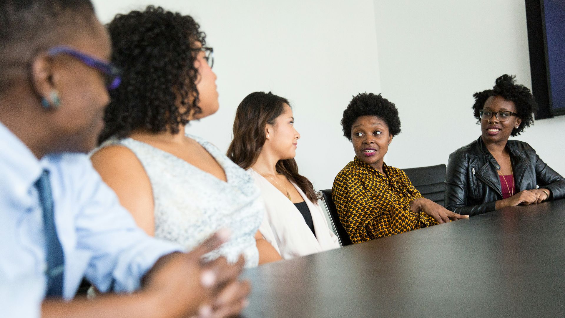 five people sitting at table and talking