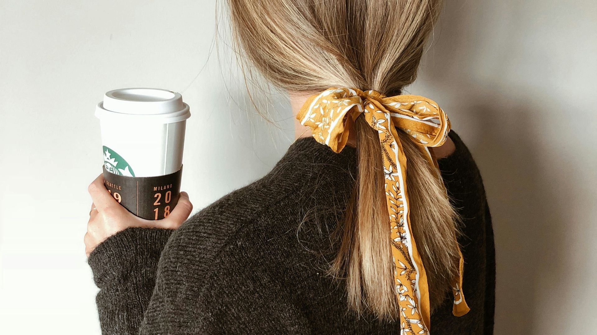 woman in black sweater holding starbucks coffee cup