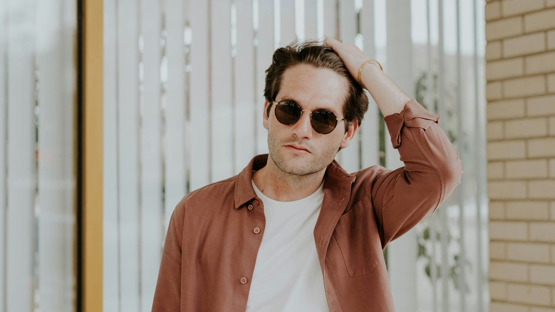 man in brown jacket near window blinds