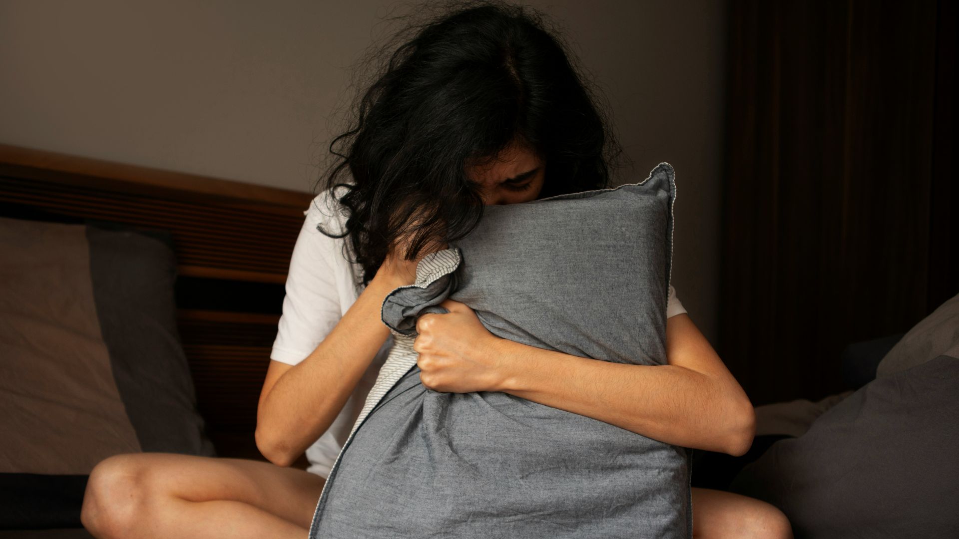 A woman sitting on a bed holding a pillow