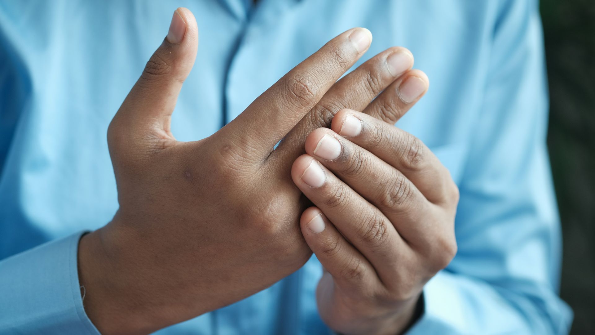 person in blue shirt showing left hand