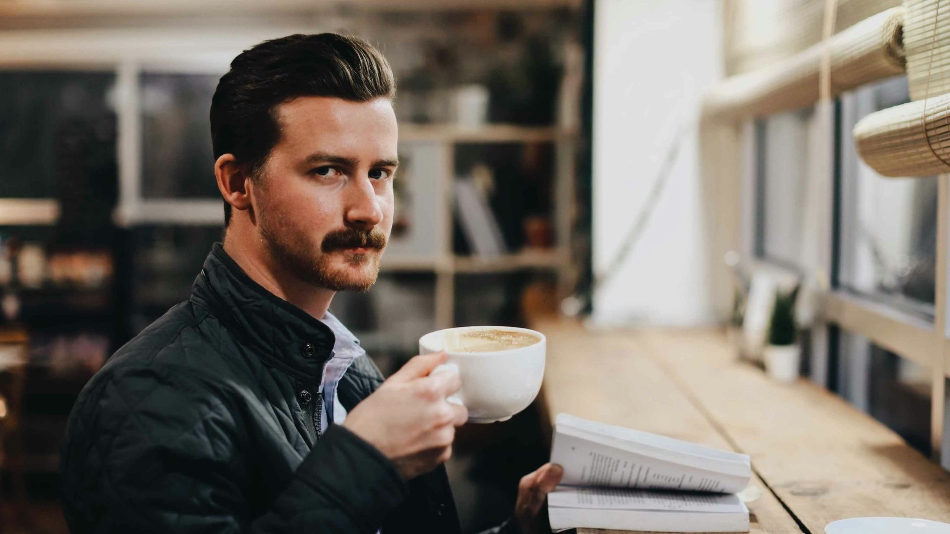 man in black leather jacket holding white ceramic mug