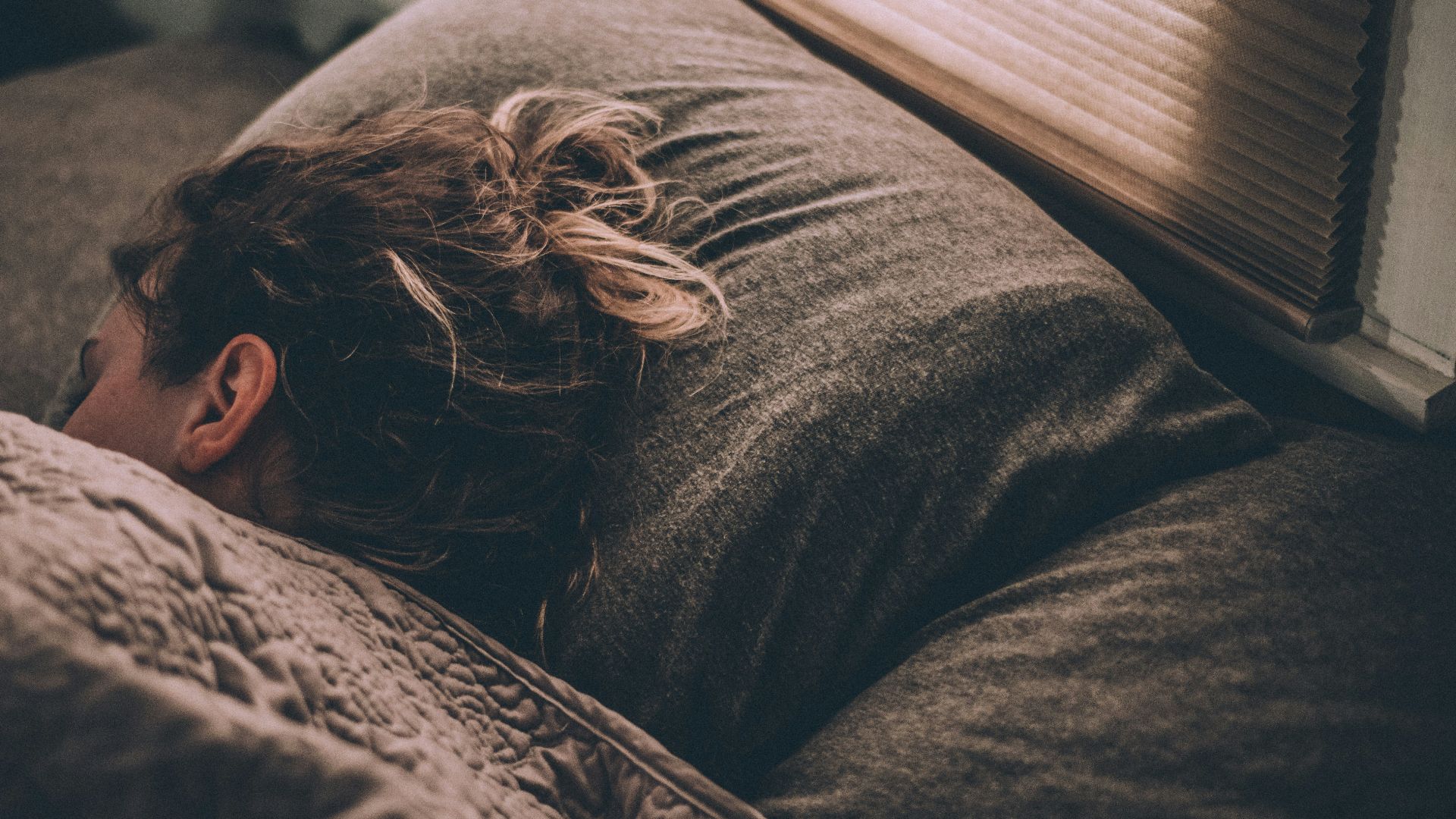 woman sleeping on bed under blankets