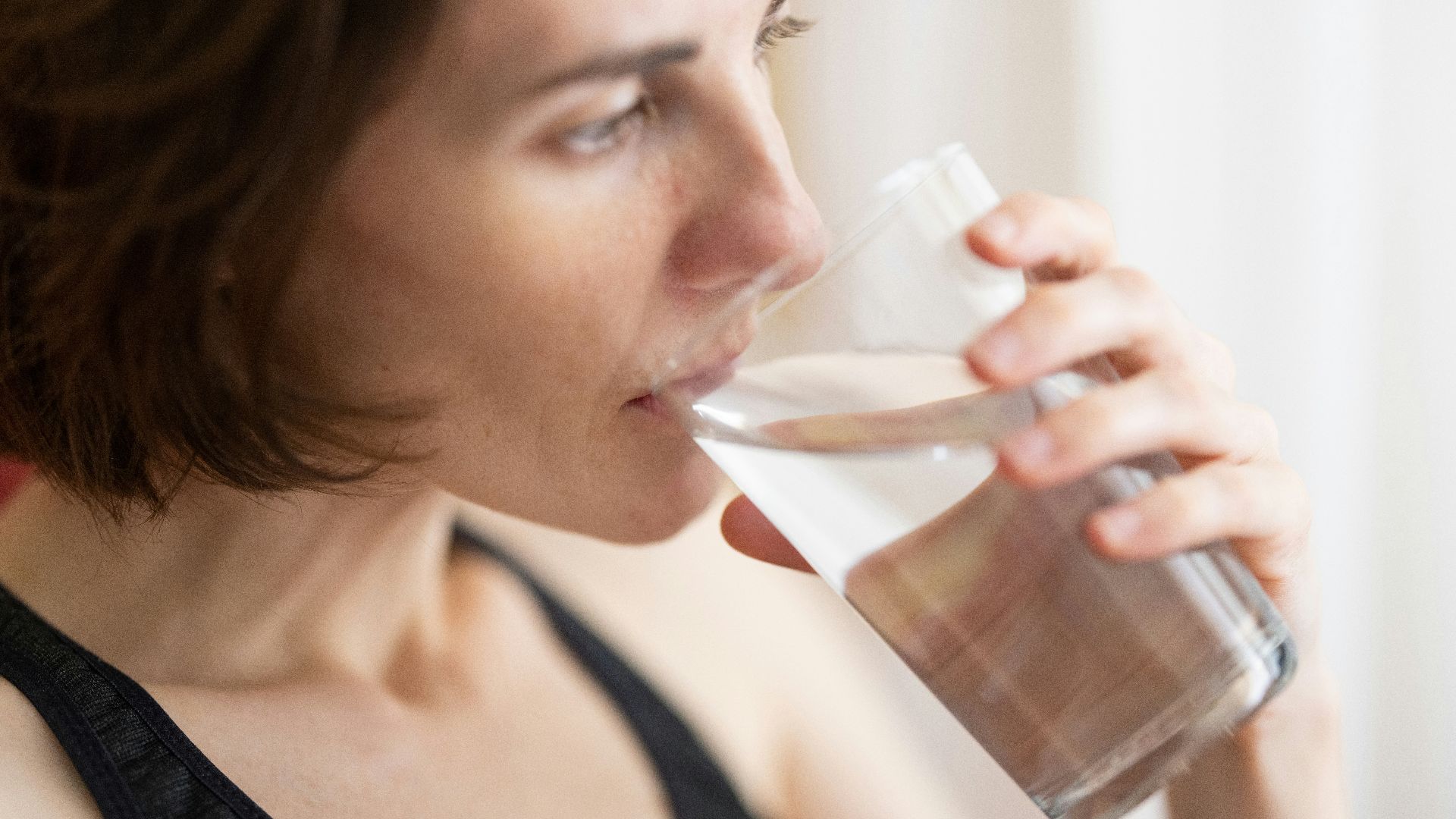 woman in black tank top drinking water