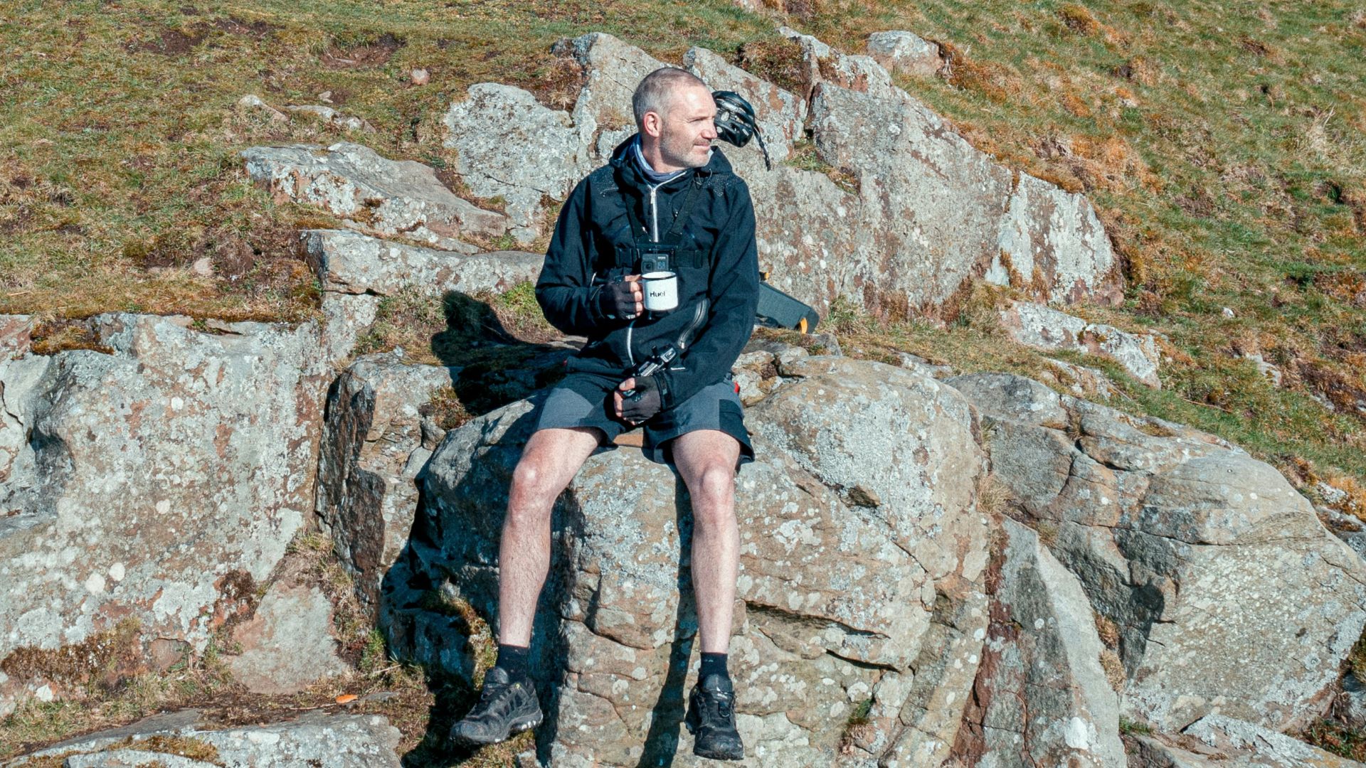 a man sitting on top of a rock next to a bike