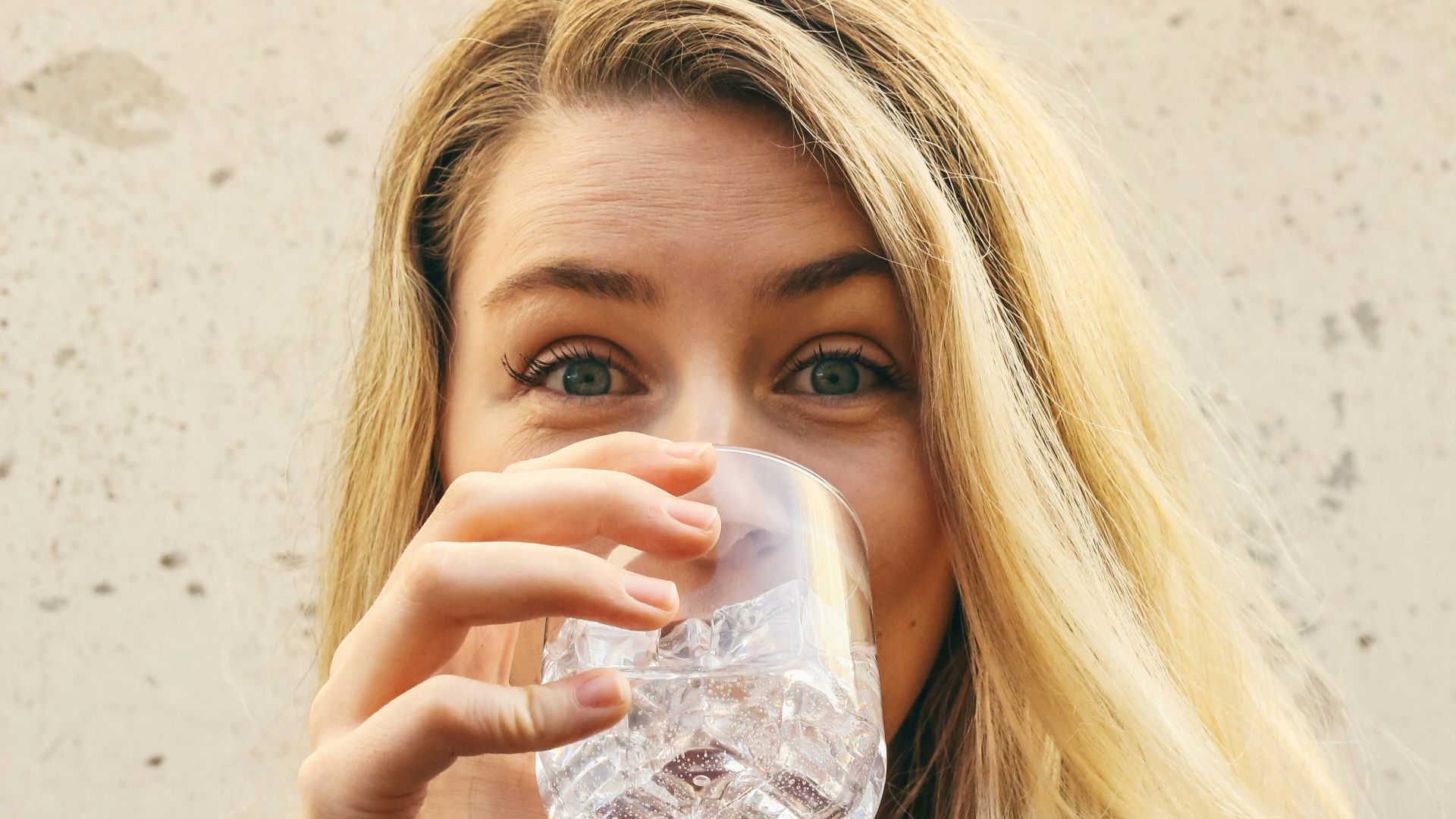 woman in white crew neck shirt drinking water