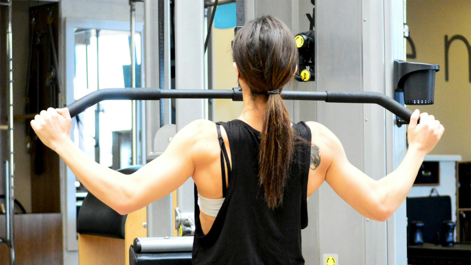 woman wearing black sleeveless top using gym equipment